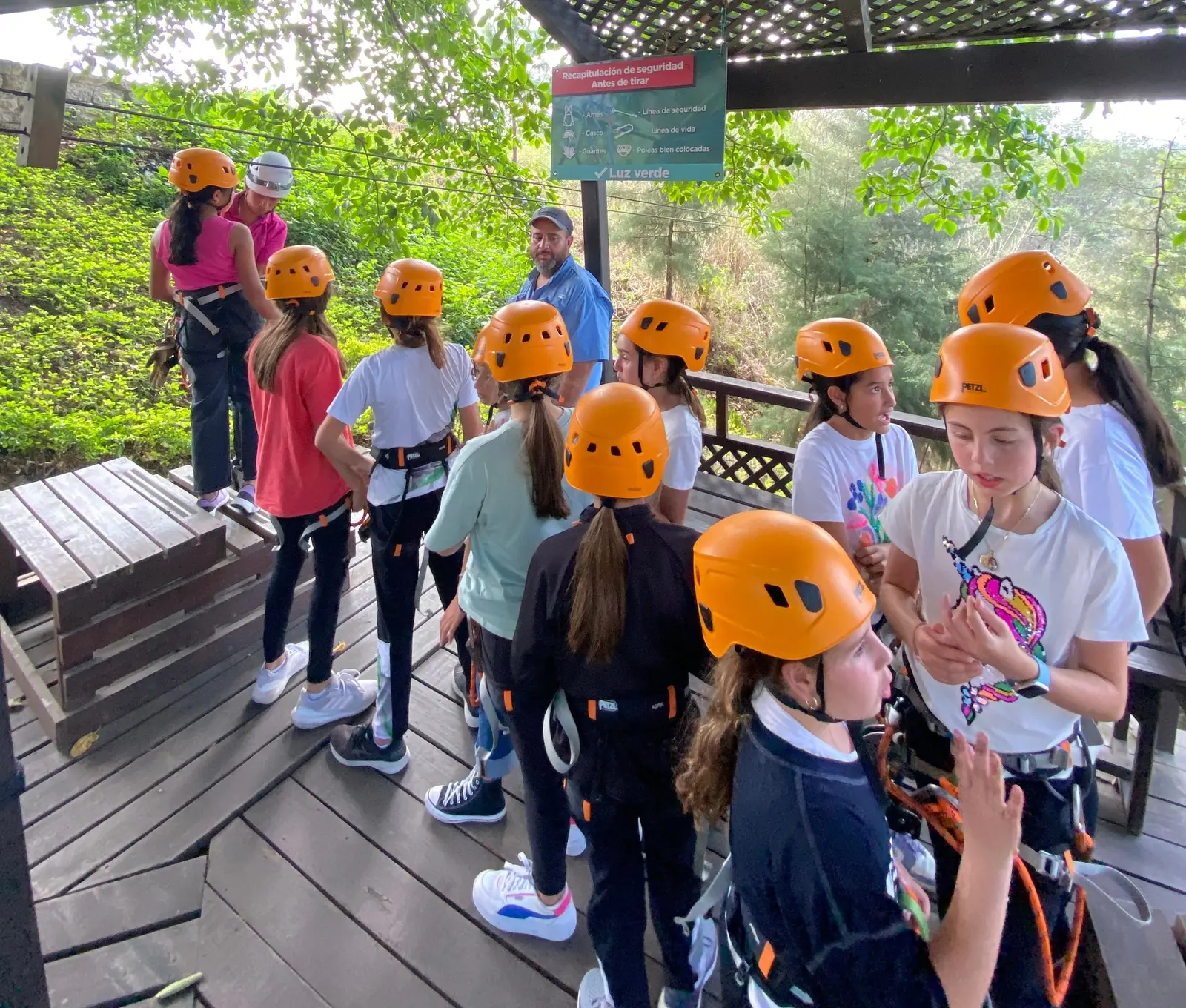 Grupo con cascos naranja y arneses en la estación del canopy, listo para volar