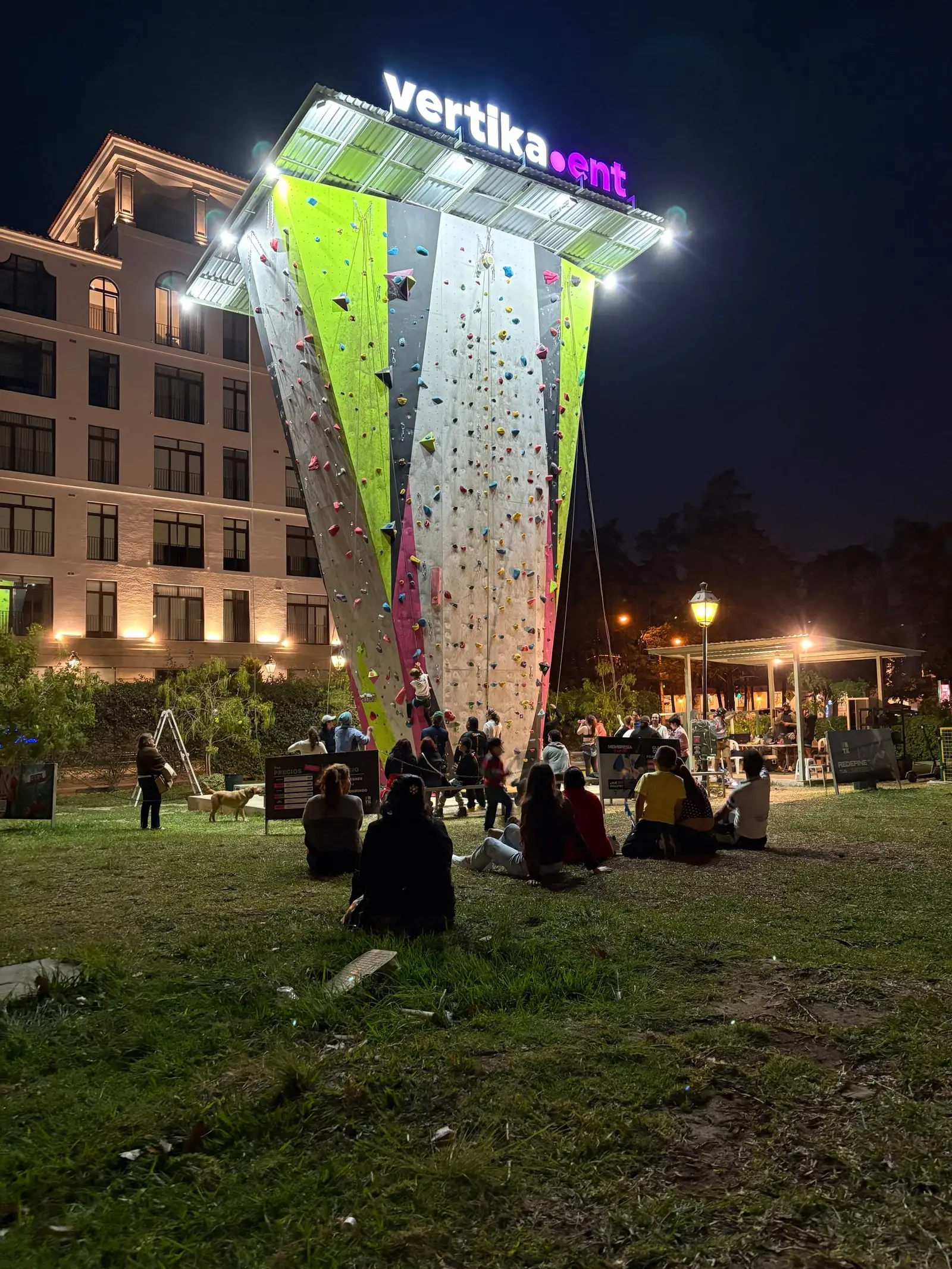 El Muro iluminado de noche, con gente en el jardín