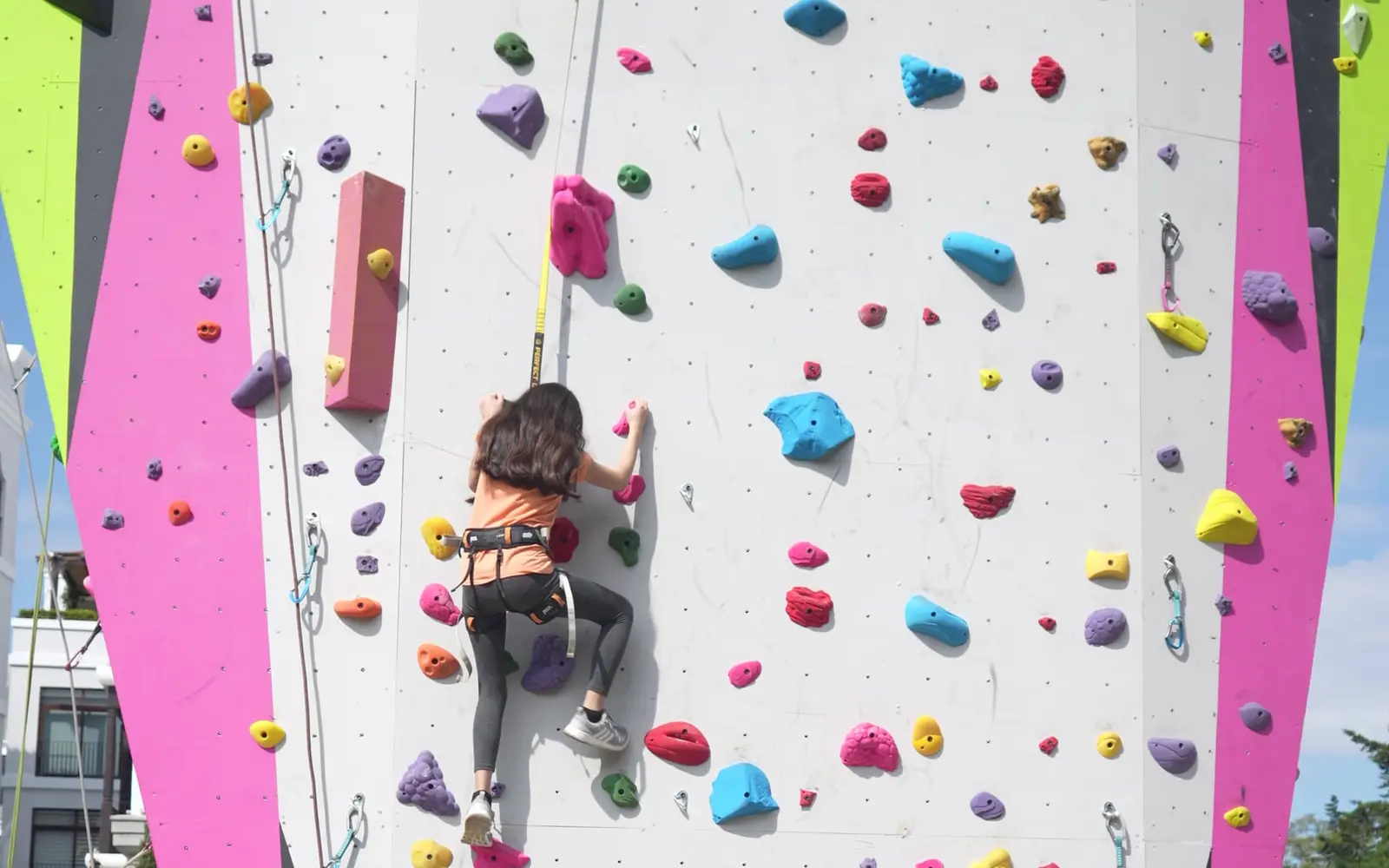Escaladora subiendo la pared rosada de El Muro, en Cayalá